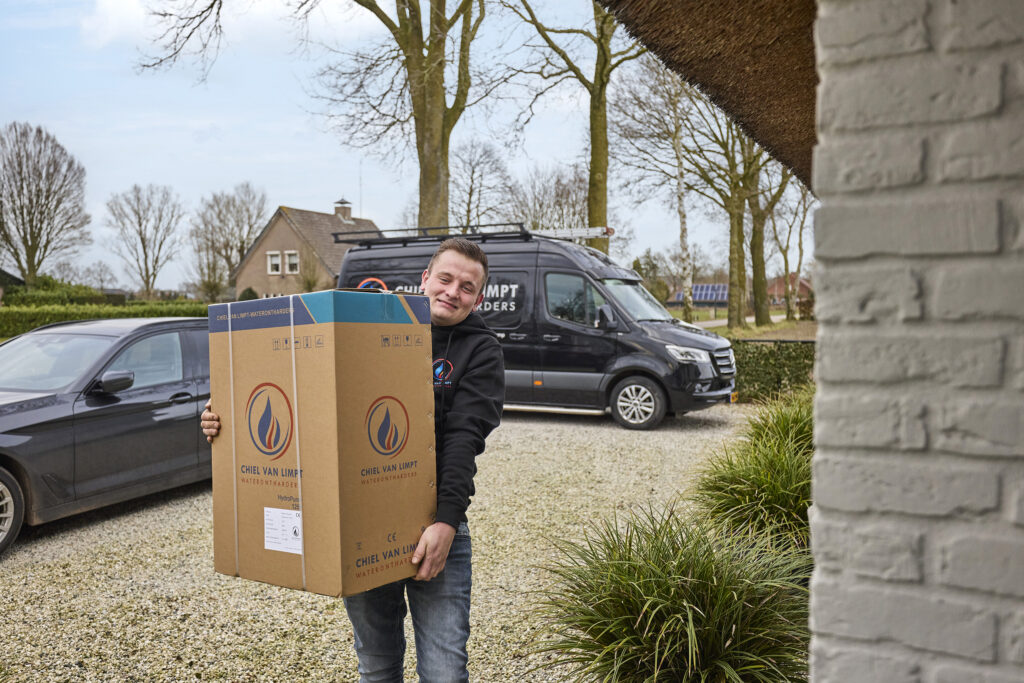 Chiel van Limpt die een waterontharder naar de deur draagt. Een waterontharder werkt tegen hard water in de kempen.